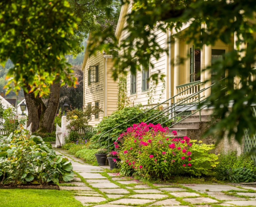 Jardín con flores y fachada histórica del Walaker Hotel en Balestrand