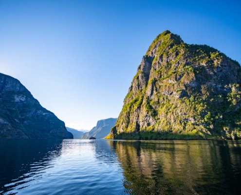 Montañas verdes reflejadas en el agua tranquila del Nærøyfjord