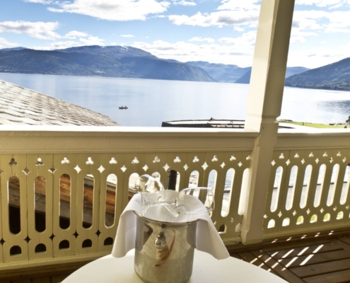 terraza de madera del hotel kviknes con mesa y cubitera frente al fiordo en balestrand