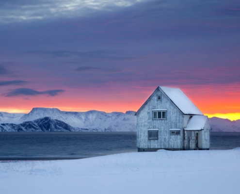 Casa de madera rodeada de nieve junto al mar en Alta, Noruega.