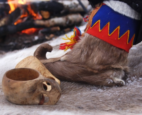 Botas tradicionales sami y tazas de madera junto al fuego en Alta, Noruega.