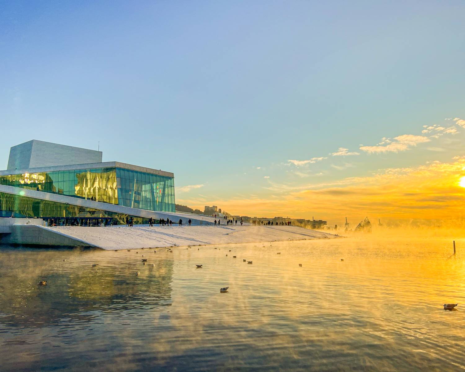 Ópera cubierta de nieve junto al fiordo bajo la luz dorada en Oslo, Noruega.
